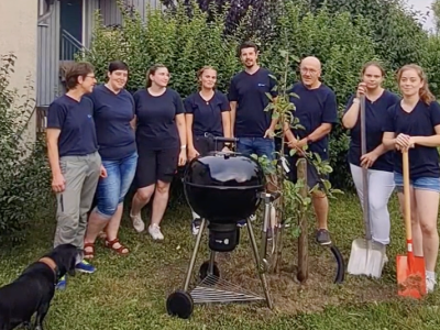 Das Team von Tierärzte Team Tiefenbach steht um den gepflanzten Baum. Daneben steht ein Grill.